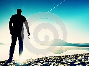 A sports man staying at the gorgeous sunset beach with glasses in hand and enjoying sunset