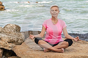 Sports mature woman at the beach make meditate exercises