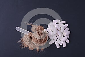 Sports nutrition on a black background. Protein and dietary supplements in powder and in tablets.