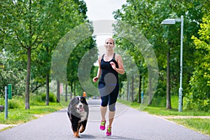 Sports outdoor - young woman running with dog in park