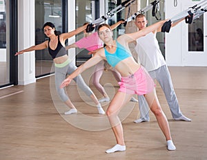 Sports people perform an exercise for stretching muscles using a special suspended structure