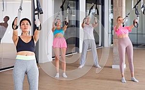 Sports people perform an exercise for stretching muscles using a special suspended structure