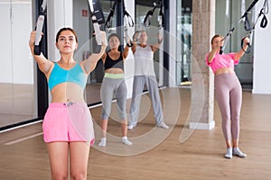 Sports people perform an exercise for stretching muscles using a special suspended structure