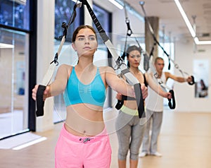Sports people perform an exercise for stretching muscles using a special suspended structure