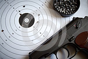 A sports pistol on the background of a target with bullet holes and lead bullets