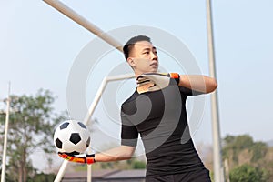 Sports and recreation concept a male goalkeeper standing in front of the goal throwing a ball as distributing in to a player after