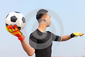 Sports and recreation concept a male goalkeeper standing in front of the goal throwing a ball as distributing in to a player after