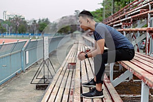 Sports and recreation concept a male youth sitting on a grandstand at the border of a staduim