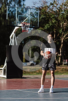 Sports and recreation concept a young male basketball player holding a basketball alone in the basketball court background