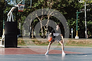 Sports and recreation concept a young male basketball player holding a basketball alone in the basketball court background