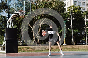 Sports and recreation concept a young male basketball player holding a basketball alone in the basketball court background