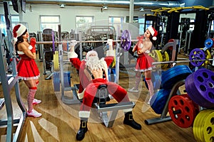 Sports Santa Claus with girls in Santa`s costumes in the gym on