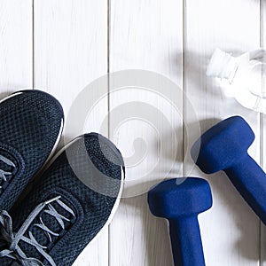 Sports set. Blue women's sneakers, blue dumbbells and white scales stand on a white background