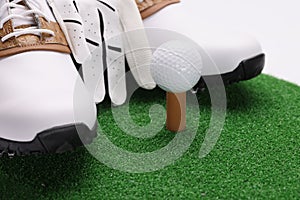 Sports shoes with gloves and golf ball lying on green grass closeup