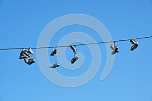 Sports shoes are hanging on wires.Sneakers suspended by laces on electrical wires