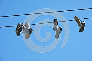 Sports shoes are hanging on wires.Sneakers suspended by laces on electrical wires