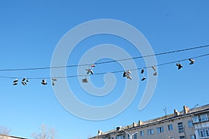 Sports shoes are hanging on wires.Sneakers suspended by laces on electrical wires
