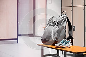 Sports shoes, sport backpack and sport water bottle in gym locker room
