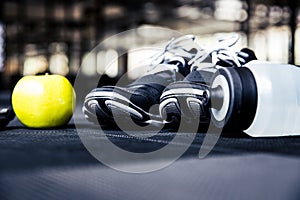 Sports sneakers, bottle with water and green apple