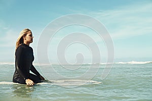 Sports, space and woman in ocean on surfboard to relax with sports, fitness or exercise in summer. Nature, sea and wave