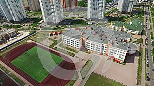 Sports stadium in schoolyard on high rise buildings. Aerial view football field