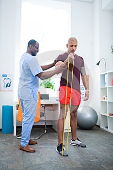 Sports therapist assisting patient doing exercises for arms