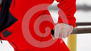 A sports trained man performs push-ups on parallel bars in the winter in the open air. Close-up of a man`s hands