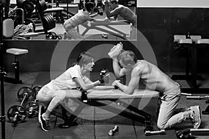 Sports training. arm wrestling muscular man and girl at gym