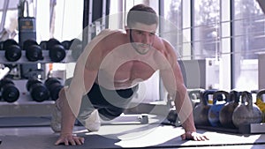 Sports training, muscular sportsman with beautiful athletic body does pushups during power workout at fitness club
