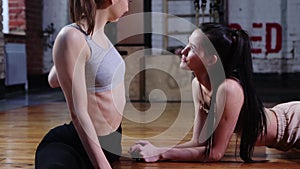 Sports - two skinny women training together in the gym - doing stretching exercises