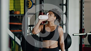 Sports and water balance. Young pretty african american woman athlete drinking water at gym, free space