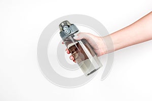 Sports water bottle in a woman`s hand on a light background