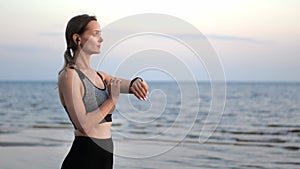 Sports woman checking heart rate on smartwatch enjoy jogging running sunset beach sea waves slowmo