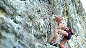 Sports woman with coloured hair climbing the rock having workout in mountains.