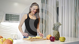 Sports woman is cutting an orange on a wooden board. Fresh fruits. Healthy lifestyle.