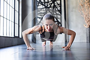 Sports woman dressed in a gym suit doing push-ups on the floor