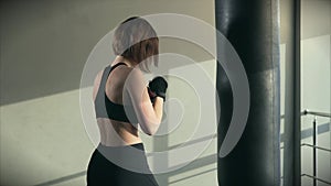 Sports woman is engaged in boxing, trains with a boxing bag in the fitness club