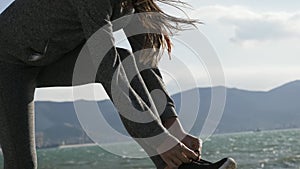 Sports woman getting ready for run tying laces of running shoes on the beach