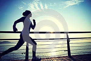Sports woman running on wooden boardwalk sunrise seaside