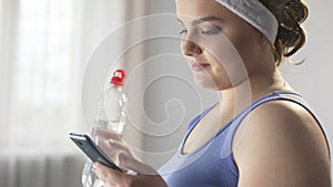 Sports woman scrolling her smartphone looking for new ways of weight loss