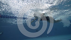 Sports woman swimming butterfly stroke in blue water pool underwater view