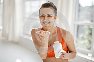 Sports woman takes supplements or vitamins at gym