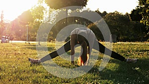 Sports woman try sits on a twine, doing fitness and stretching exercises, training in park at sunset, healthy and sporty