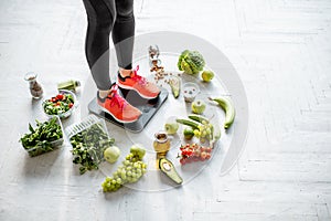 Sports woman weighing with healthy food around