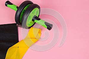 Sports yellow elastic band . Sports equipment. Yellow elastic band on a pink background. Green dumbbell. Sports sneakers