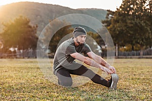 Sports and yoga. A man in sportswear warming up on the grass before training. Copy space