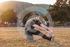 Sports and yoga. A man in sportswear warming up on the grass before training. Tint