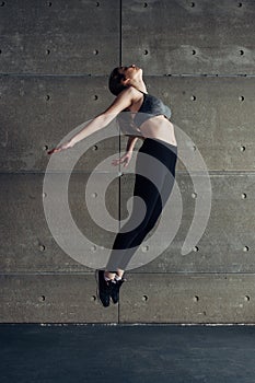 Sports young woman doing back bend jump