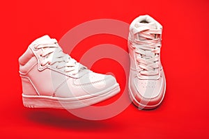 Sports youth shoes on red background close-up. white leather lace-up sneakers