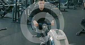 sportsman with artificial legs limb working out in gym on rowing machine